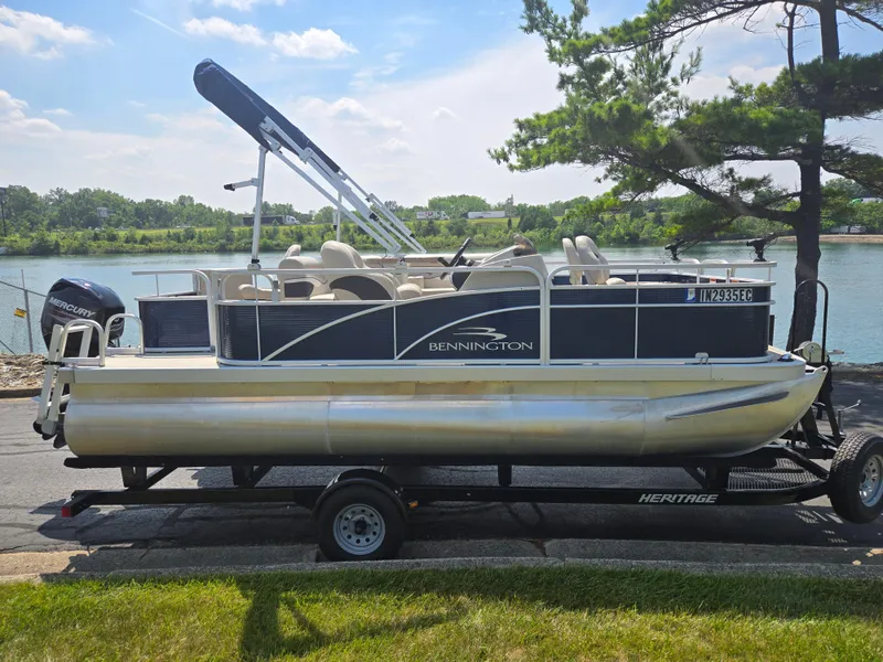 Slide: The Image of 2019 Bennington 188 SFV pontoon boat on trailer by a lake. - 9