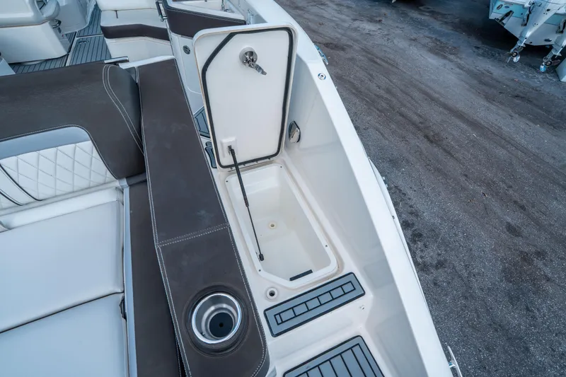 Slide: The Image of 2018 Sea Ray SLX 310 boat interior with open storage compartment and cup holder. - 31