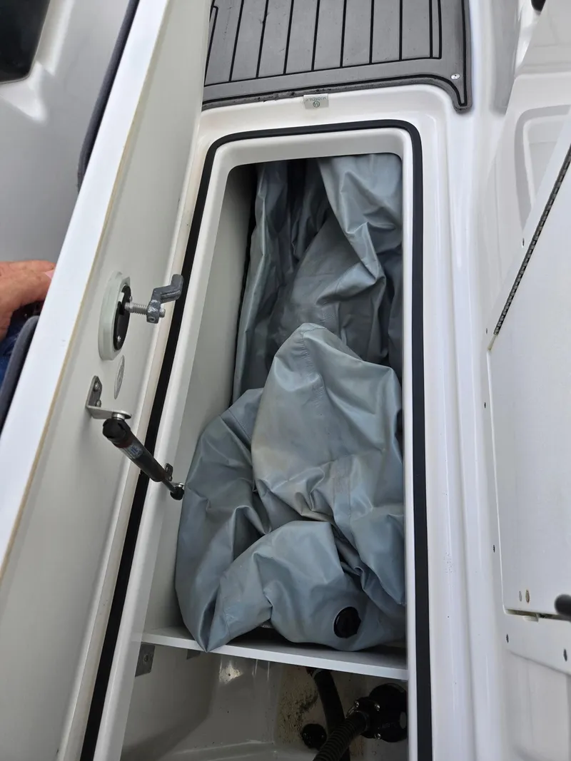 Slide: The Image of Storage compartment of a 2018 Yamaha Boats 212X, containing a folded tarp. - 14