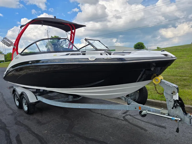 Slide: The Image of 2018 Yamaha Boats 212X on trailer, black and white design, parked on asphalt with cloudy sky. - 5