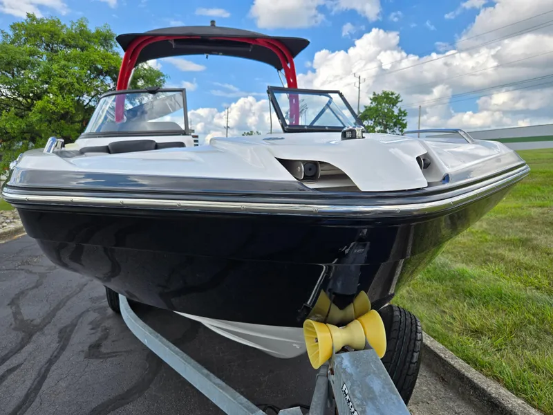 Slide: The Image of 2018 Yamaha Boats 212X on trailer, sleek design, blue and white, outdoors, under blue sky. - 6