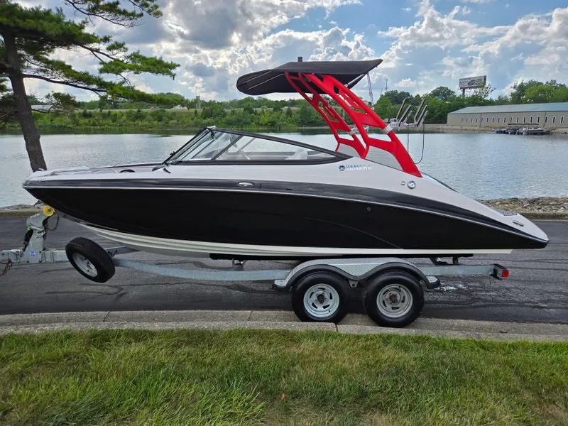 Slide: The Image of 2018 Yamaha Boats 212X on trailer by a lake, under a cloudy sky. - 9