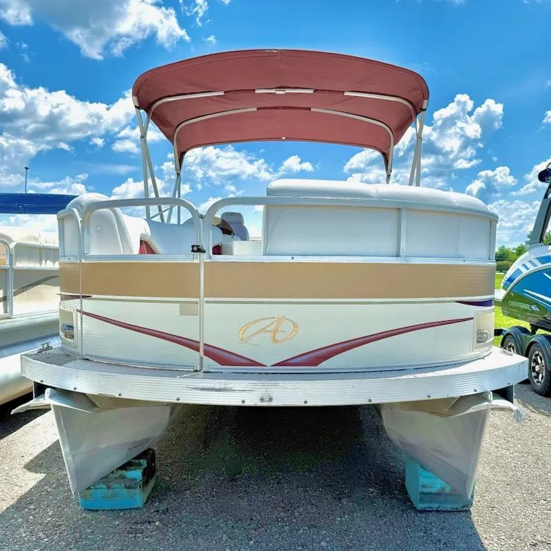Slide: The Image of 2005 Avalon EXCALIBER 2325 pontoon boat with canopy, parked on land under a blue sky. - 2