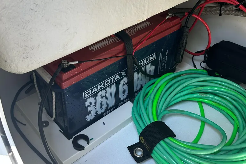 Slide: The Image of Battery compartment of 2021 Sportsman Masters 227 Bay Boat with lithium battery and coiled green cable. - 16