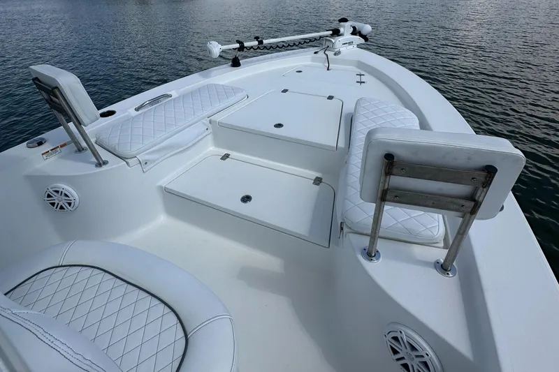 Slide: The Image of 2021 Sportsman Masters 227 Bay Boat with white seating and storage compartments on calm water. - 7