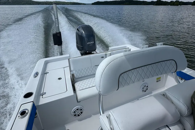 Slide: The Image of 2021 Sportsman Masters 227 Bay Boat cruising on a lake, showcasing rear seating and motor. - 8