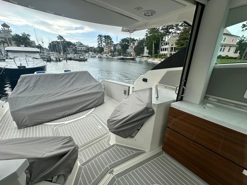 Slide: The Image of 2023 Tiara Yachts 43 LE deck view at marina with covered seating. - 12