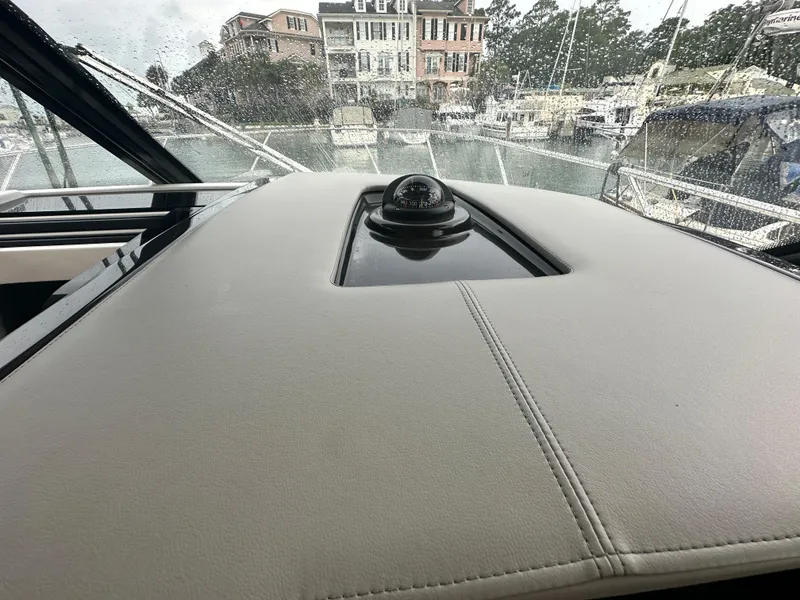Slide: The Image of 2023 Tiara Yachts 43 LE dashboard with compass, rainy marina view. - 22