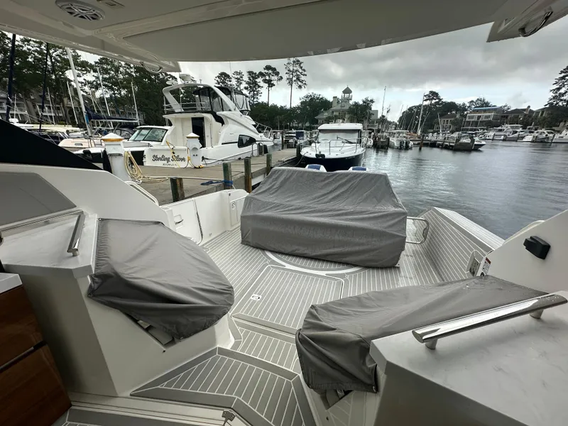 Slide: The Image of 2023 Tiara Yachts 43 LE at marina, covered seating, overcast sky. - 24