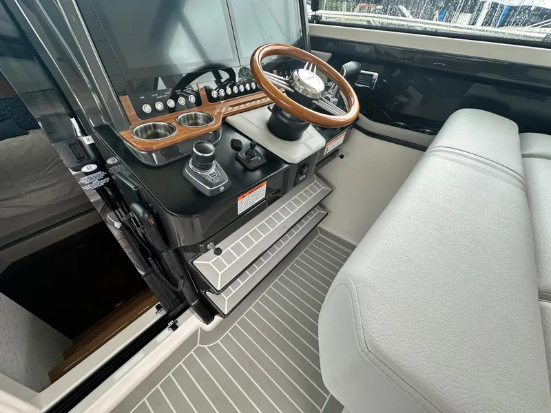 Slide: The Image of 2023 Tiara Yachts 43 LE helm with modern controls and wooden steering wheel. - 27