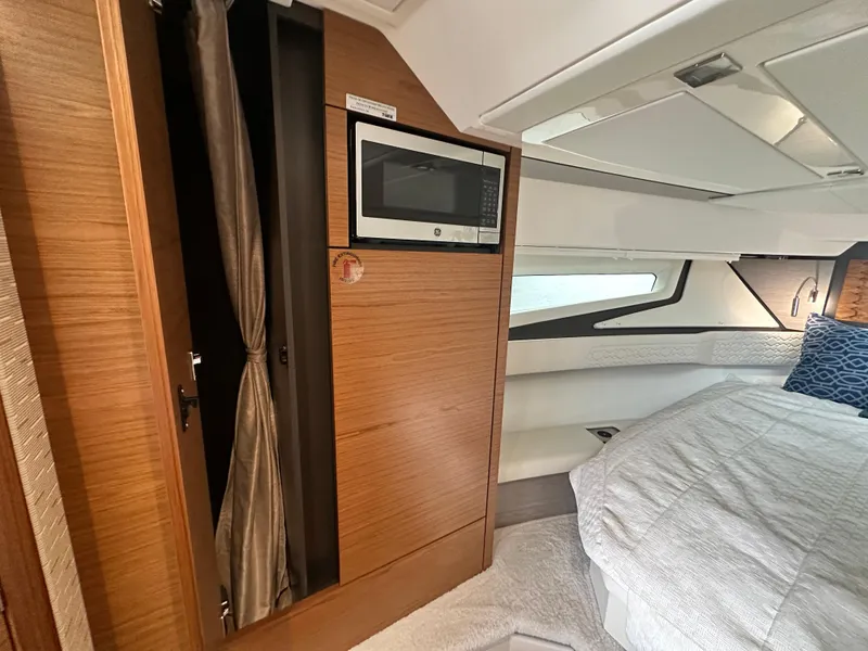 Slide: The Image of 2023 Tiara Yachts 43 LE interior with microwave, wood paneling, and cozy bedding. - 38