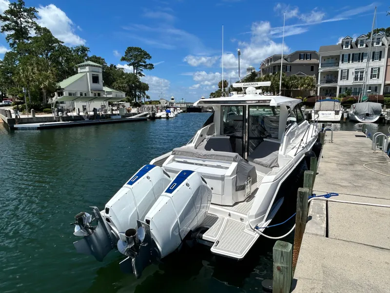 Slide: The Image of 2023 Tiara Yachts 43 LE docked at a marina under a clear blue sky. - 6