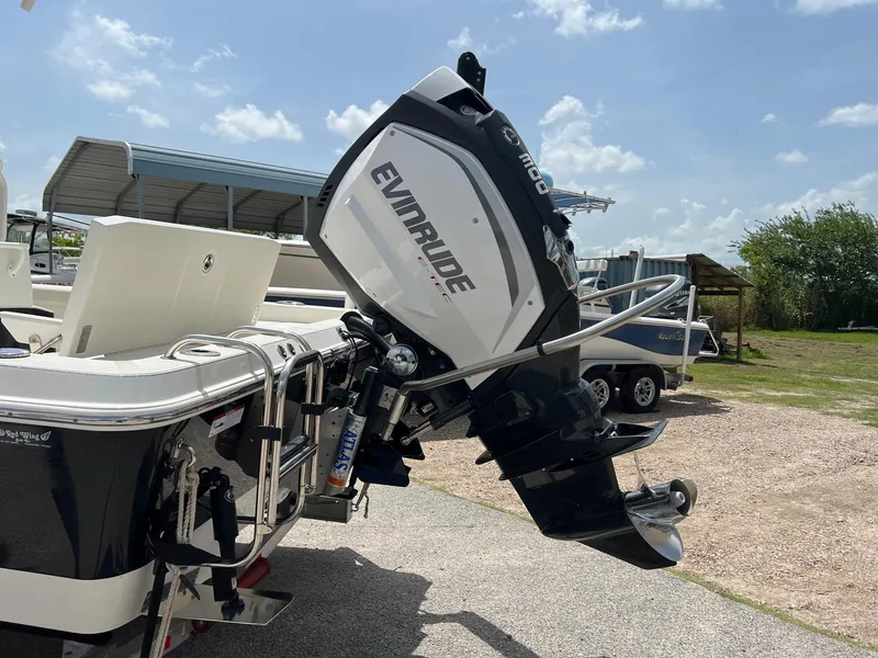 Slide: The Image of 2015 Ranger 2510 Bay boat with Evinrude outboard motor, parked outdoors under a sunny sky. - 4