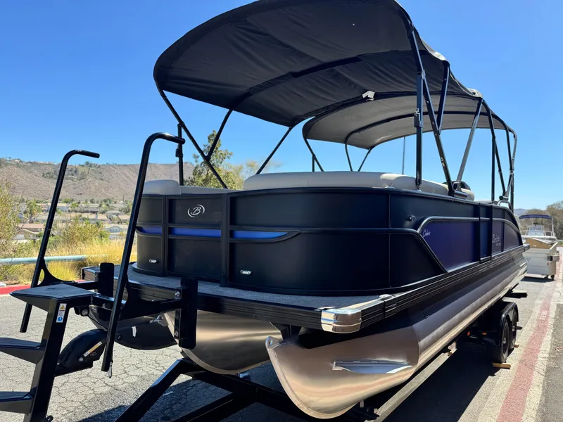 Slide: The Image of 2023 Barletta Cabrio 24UC pontoon boat with canopy on trailer, outdoor setting. - 3