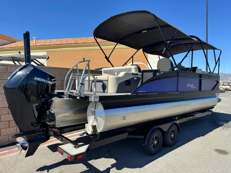 Slide: The Image of 2023 Barletta Cabrio 24UC pontoon boat with Mercury engine on trailer, parked outdoors. - 6