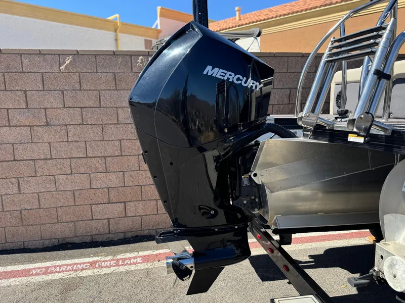 Slide: The Image of 2023 Barletta Cabrio 24UC with Mercury outboard motor, parked near a brick wall. - 7