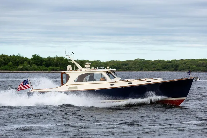 Slide: The Image of 2007 Hinckley Talaria 44 MY cruising on water with American flag, lush greenery in background. - 25