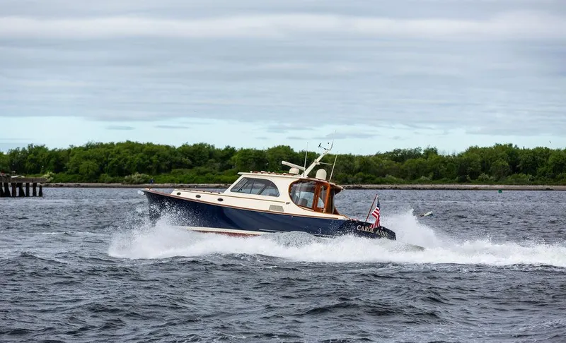 Slide: The Image of 2007 Hinckley Talaria 44 MY cruising on open water with lush green shoreline. - 40