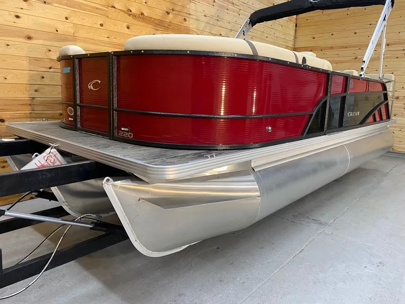Slide: The Image of 2023 Crest Classic LX 220 SLRC pontoon boat with red and black exterior in a wooden garage. - 4