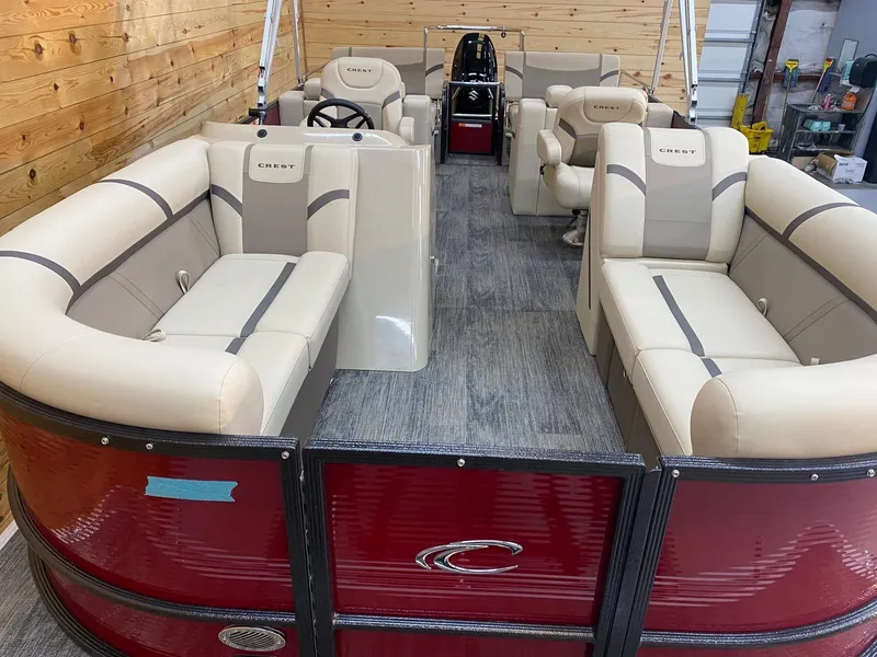 Slide: The Image of 2023 Crest Classic LX 220 SLRC pontoon boat interior with beige seating and wood paneling. - 5
