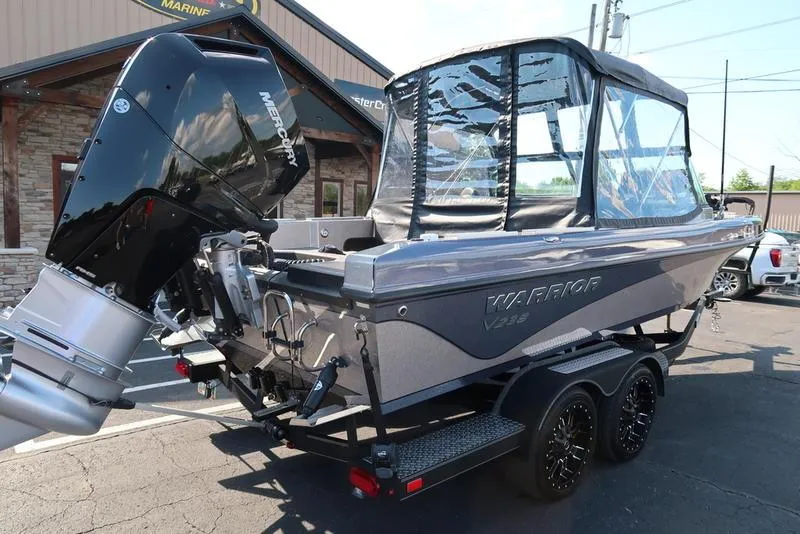 Slide: The Image of 2024 Warrior 238 DC boat with Mercury outboard engine, parked on a trailer. - 4