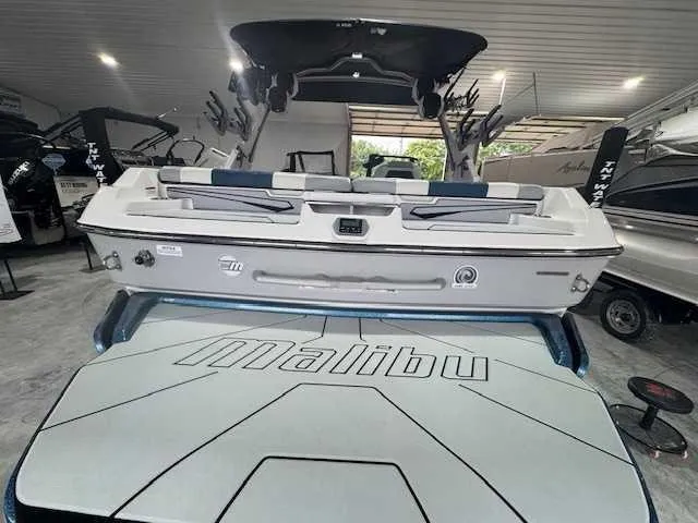 Slide: The Image of 2022 Malibu 21 LX boat in showroom, rear view with logo visible. - 8