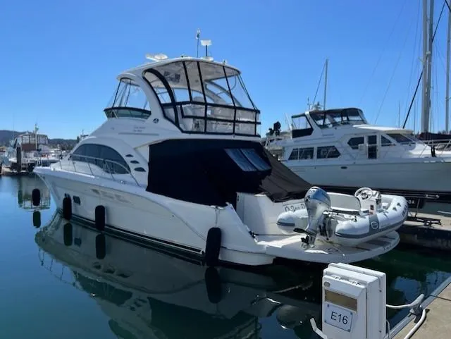 Slide: The Image of 2010 Sea Ray 520 Sedan Bridge yacht docked in marina, featuring sleek design and inflatable tender. - 2
