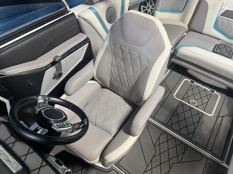Slide: The Image of 2019 Tigé ZX1 boat interior with gray and blue seating, steering wheel, and floor design. - 12