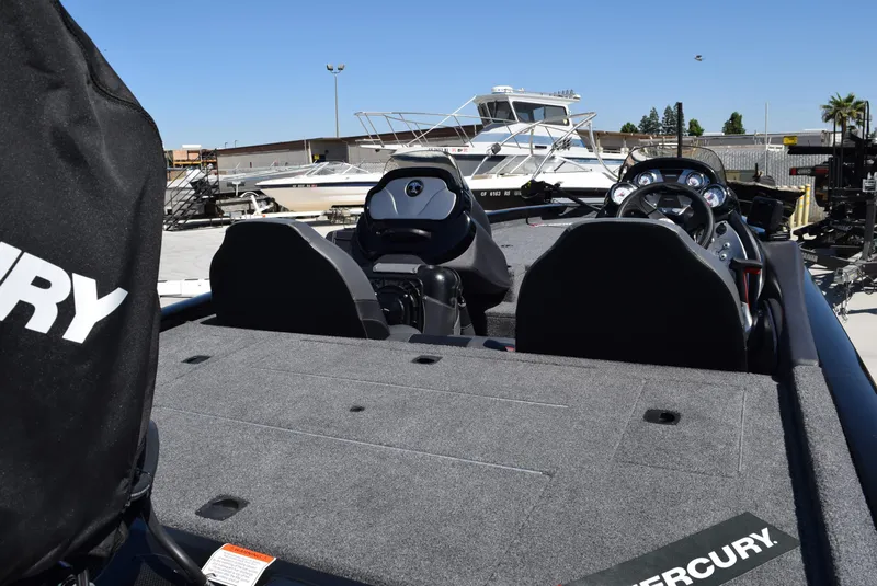 Slide: The Image of 2022 Tracker Pro Team 175 TXW boat interior with Mercury engine cover, parked outdoors. - 4