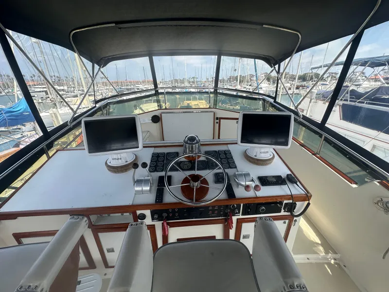 Slide: The Image of 1986 Egg Harbor SPORT FISHER helm with dual monitors and steering wheel, docked at marina. - 20