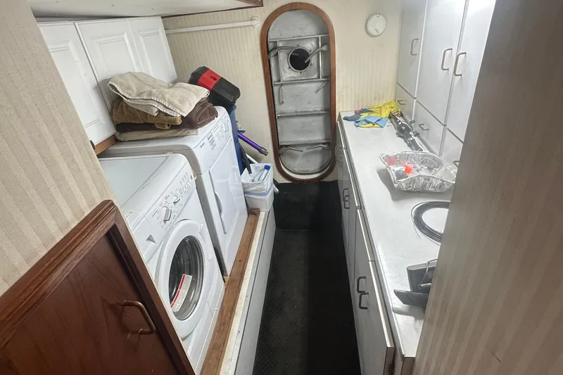Slide: The Image of Laundry area inside 1986 Egg Harbor SPORT FISHER boat with washer, dryer, and storage cabinets. - 28