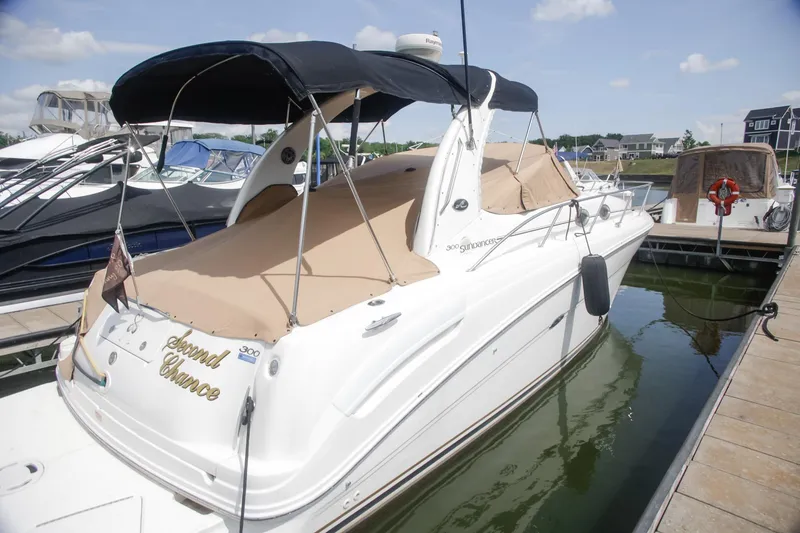 Slide: The Image of 2002 Sea Ray 300 Sundancer boat docked with beige cover and black canopy. - 11