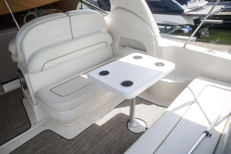 Slide: The Image of 2002 Sea Ray 300 Sundancer interior with white seating and table, docked at marina. - 6