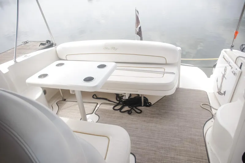 Slide: The Image of 2002 Sea Ray 300 Sundancer boat interior with seating and table on calm water. - 7