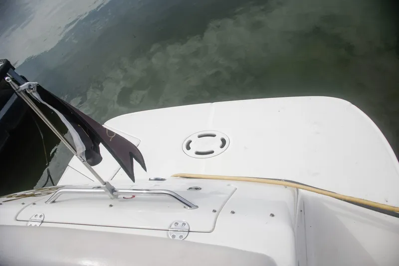 Slide: The Image of 2002 Sea Ray 300 Sundancer boat deck with flag, near calm water. - 8