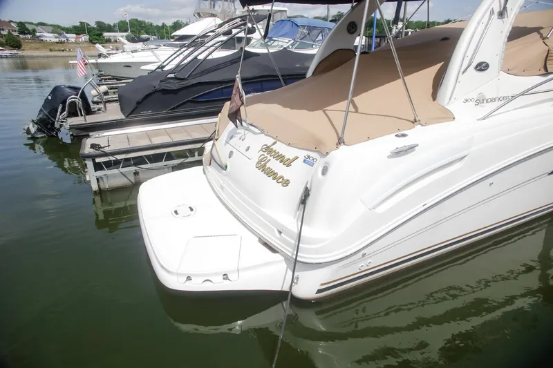 Slide: The Image of 2002 Sea Ray 300 Sundancer docked at marina, featuring tan cover and sleek design. - 9