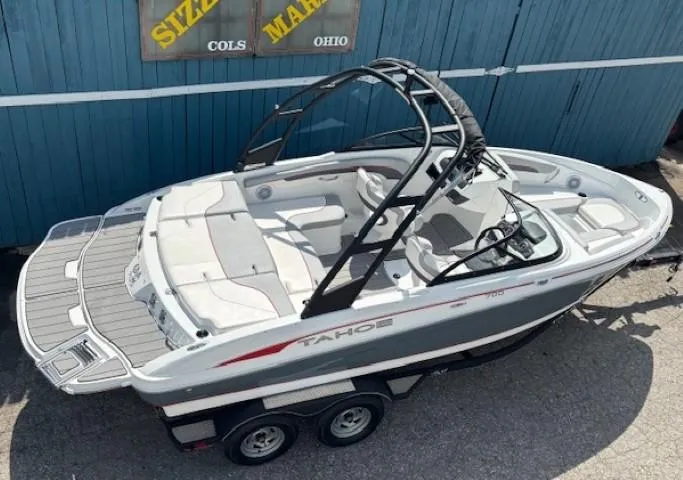 Slide: The Image of 2021 Tahoe 700 boat on trailer, white and gray design, parked near blue building. - 6