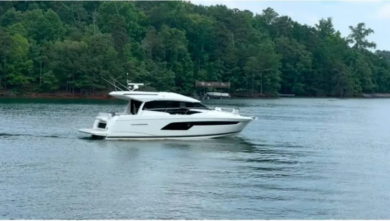 The Image of 2023 Prestige 520S yacht cruising on a serene lake with lush forest backdrop. - 0