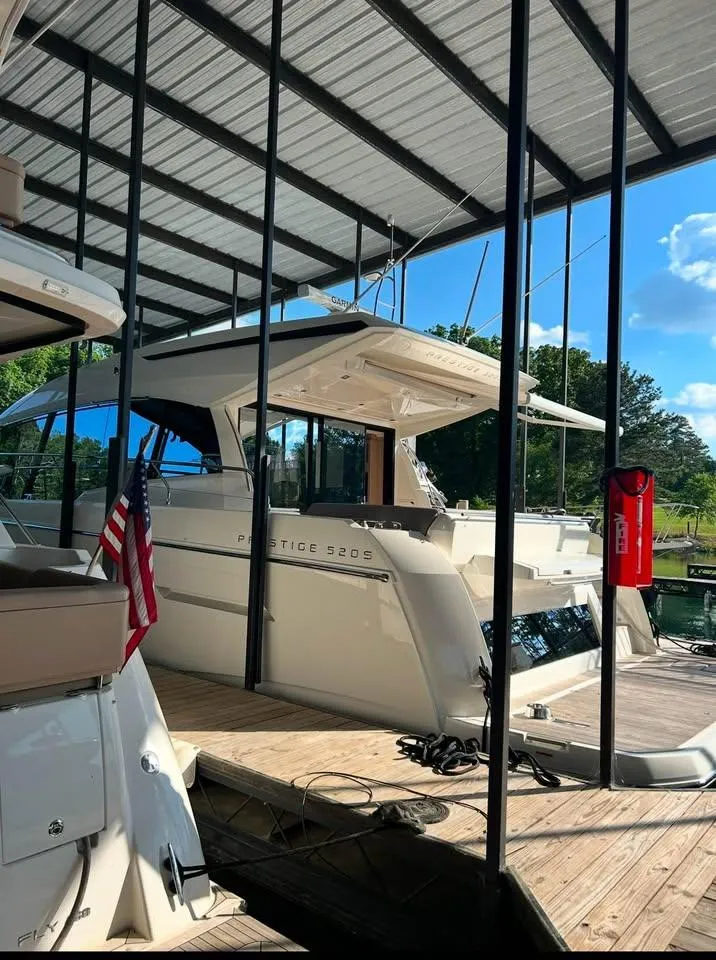 Slide: The Image of 2023 Prestige 520S yacht docked under a covered marina with clear skies. - 3