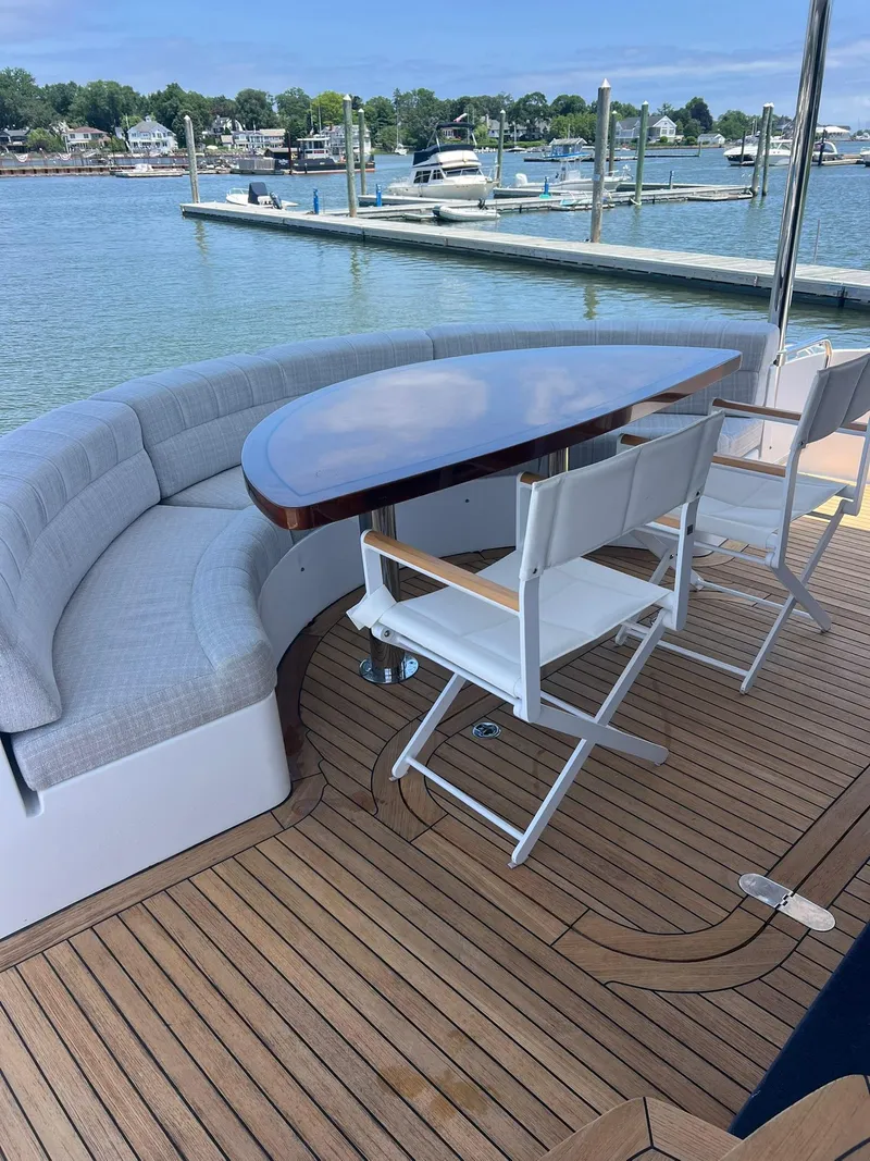Slide: The Image of Luxurious 2011 Hatteras 60 Motor Yacht deck with seating and table, docked at marina. - 14