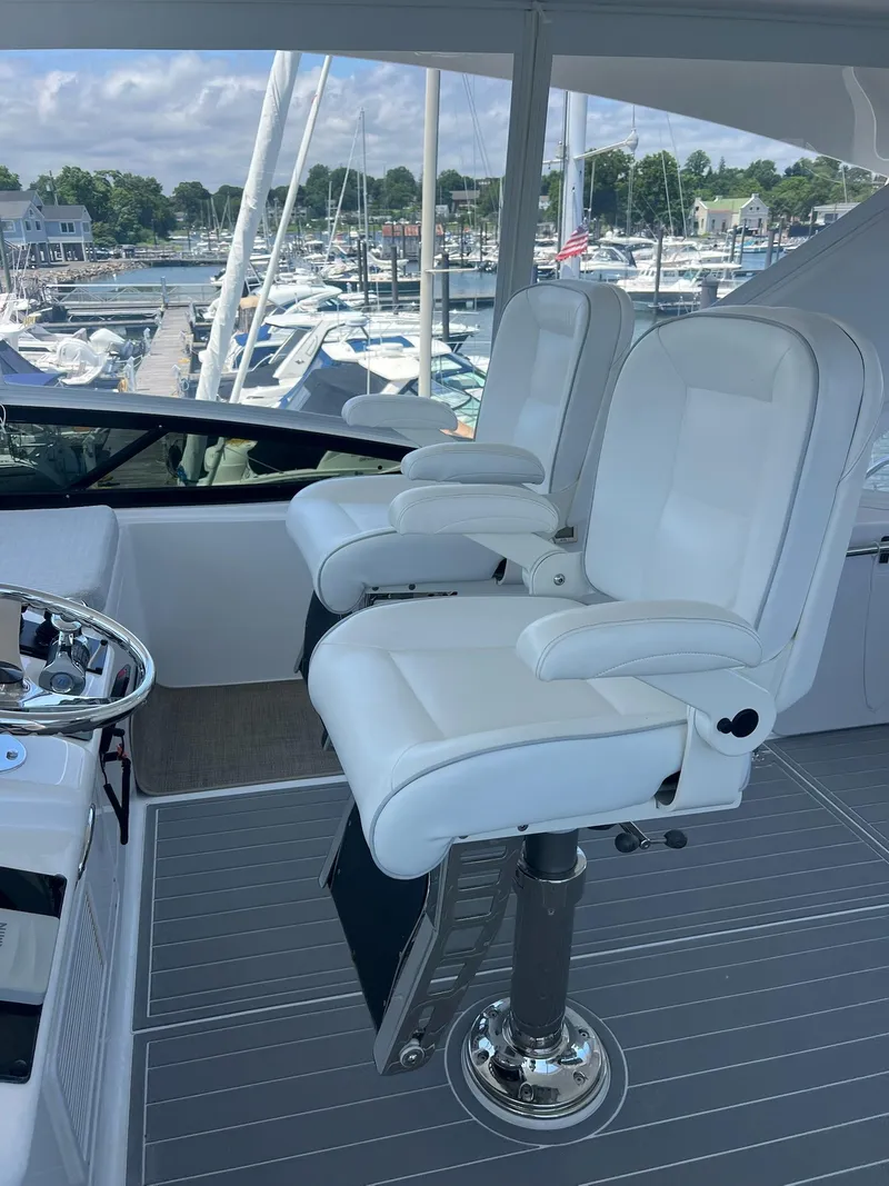 Slide: The Image of Captain's chairs on 2011 Hatteras 60 Motor Yacht, overlooking marina with boats and clear sky. - 20