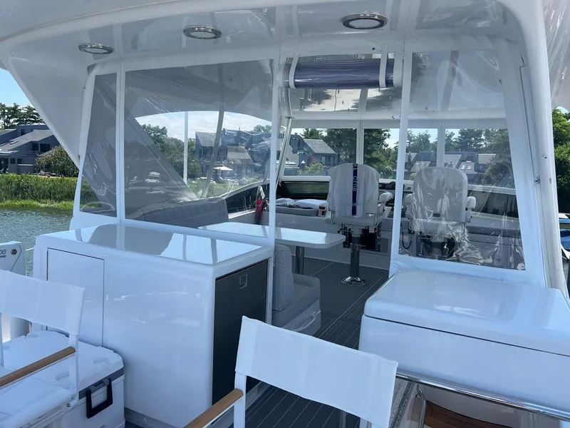 Slide: The Image of 2011 Hatteras 60 Motor Yacht interior with seating and helm, docked by waterfront homes. - 23