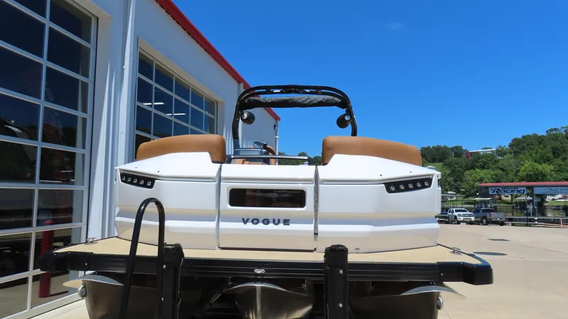 Slide: The Image of 2025 Princecraft Vogue 27 RL pontoon boat at a marina under clear blue sky. - 2