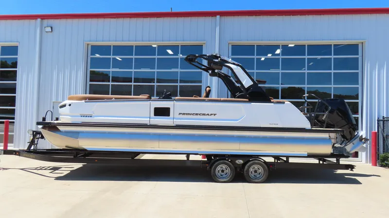 Slide: The Image of 2025 Princecraft Vogue 27 RL pontoon boat on trailer, parked outside a building. - 3