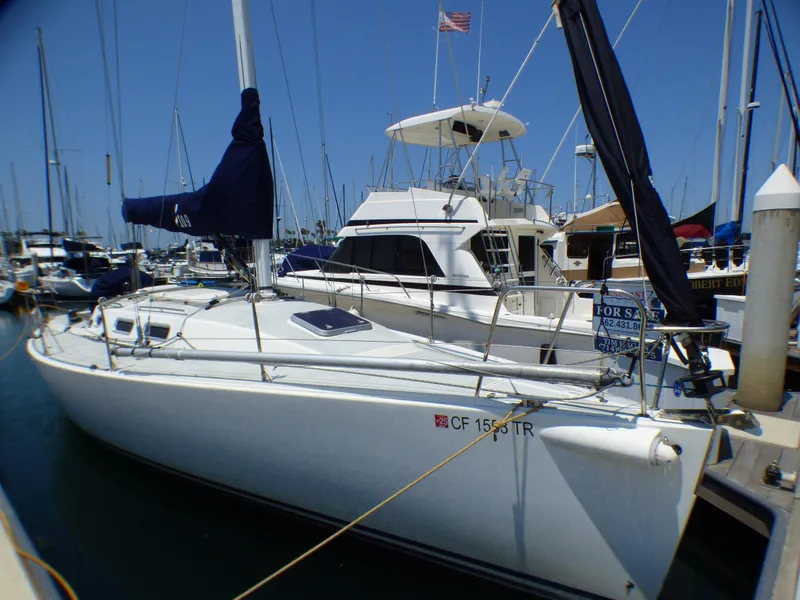 Slide: The Image of 2002 J Boats J/109 sailboat docked in marina, for sale sign visible. - 2