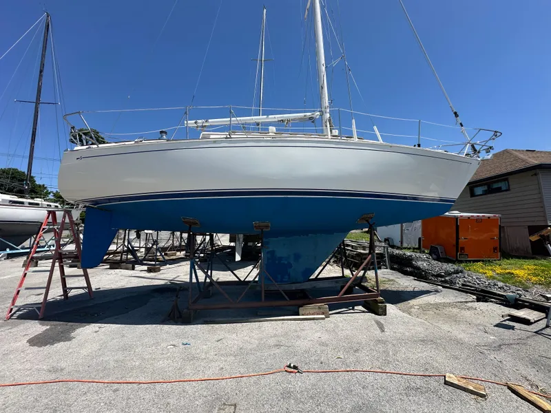 The Image of 1986 Sabre 32 sailboat on stands, blue hull, clear sky background. - 1