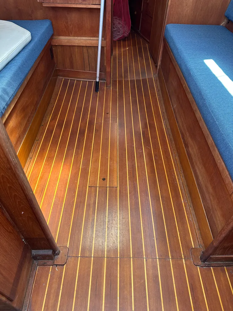 Slide: The Image of Interior of 1986 Sabre 32 sailboat with wooden flooring and blue cushioned seating. - 23