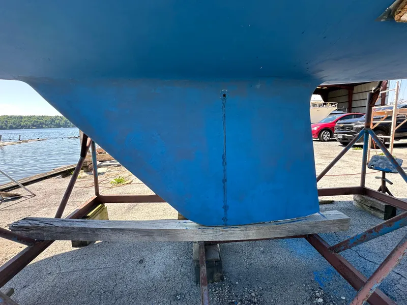 Slide: The Image of 1986 Sabre 32 sailboat keel on dry dock, with waterfront and vehicles in background. - 4