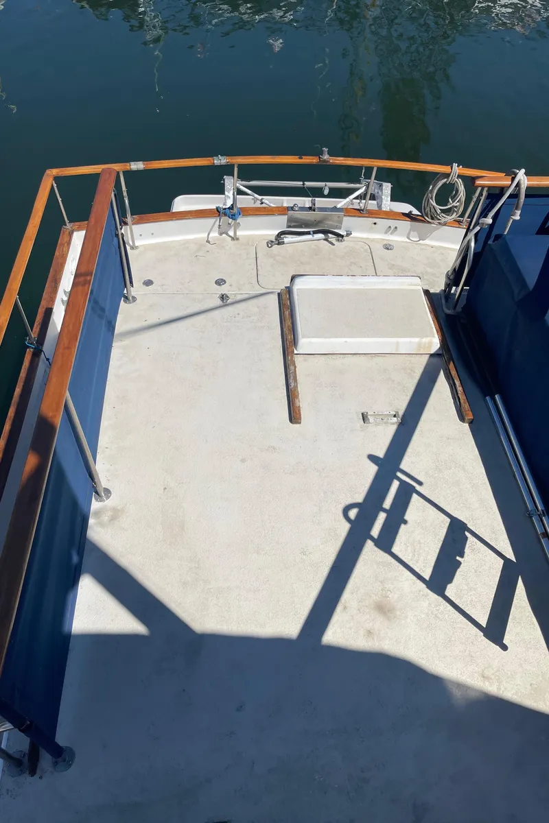 Slide: The Image of 1978 Californian Tri-Cabin Trawler deck with wooden railings and water view. - 11