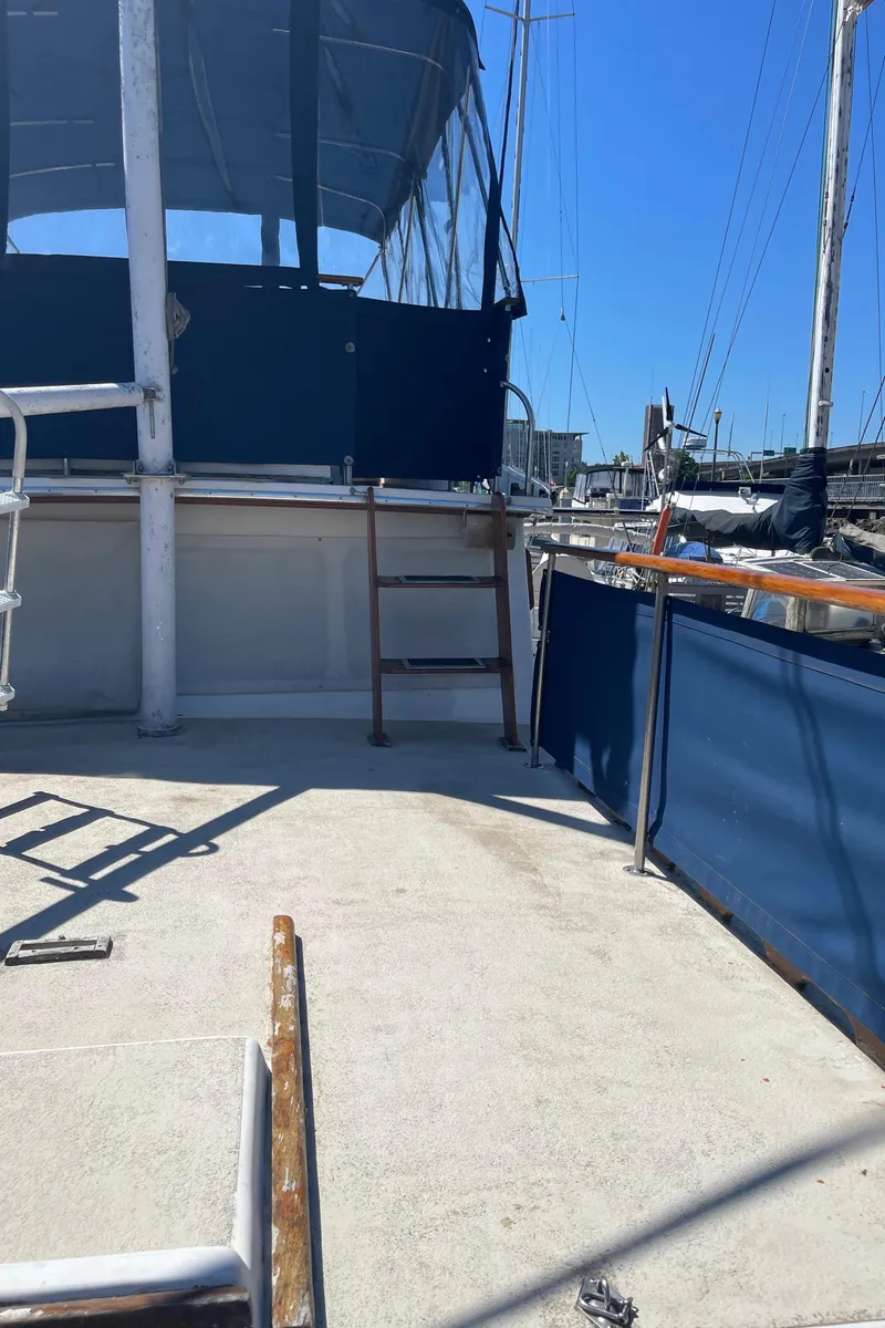 Slide: The Image of 1978 Californian Tri-Cabin Trawler deck with blue canopy and railing in marina. - 12
